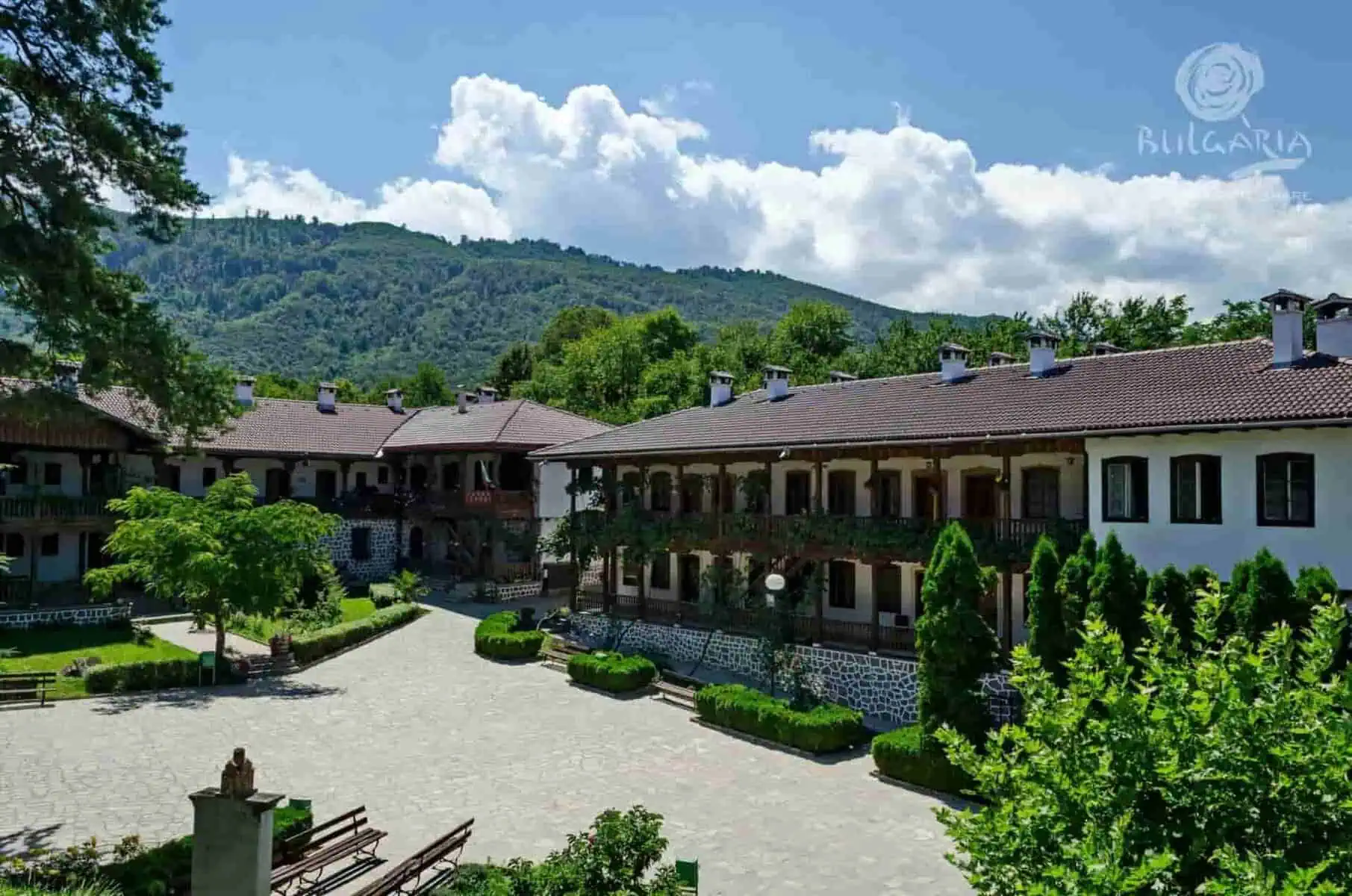 A spacious courtyard with trees and mountains in the background, enhancing the grandeur of the large building.