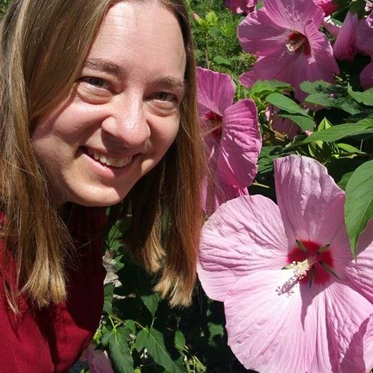 Pink hibiscus flowers and smiling woman in garden, vibrant botanical photography, outdoor floral backdrop, nature photography, colorful blooms and greenery.