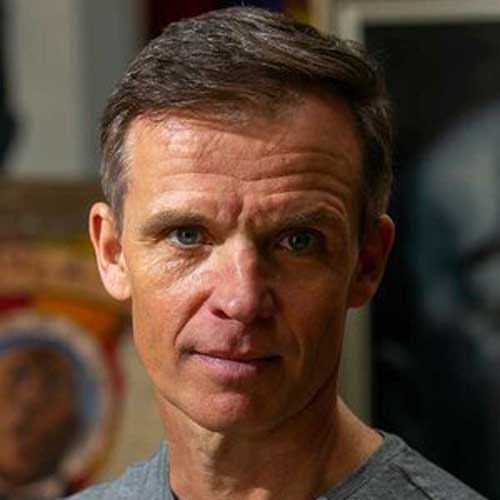 Man in casual clothing with arts and gallery decor in background at Visual Arts Passage exhibition.