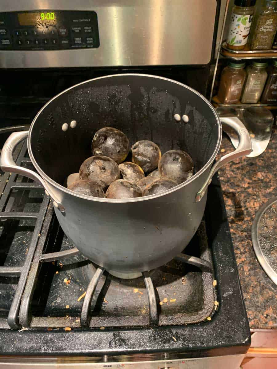 Charcoal briquettes inside a cooking pot on a stovetop for grilling or smoking food.