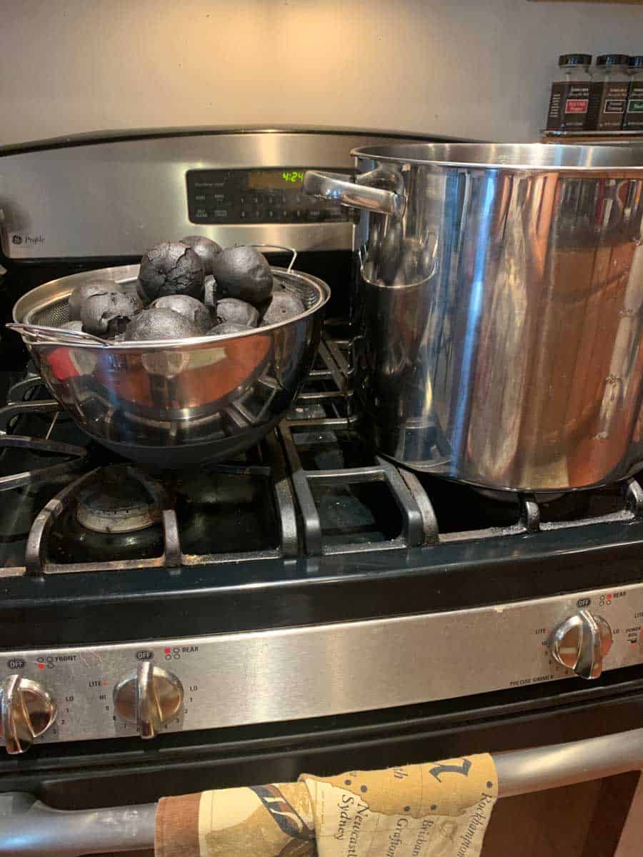 Charcoal briquettes on stove, large stockpot, kitchen cookware, cooking heat source, culinary preparation, kitchen stove setup, home cooking appliance, industrial kitchen gear, cooking essentials, food preparation tools.