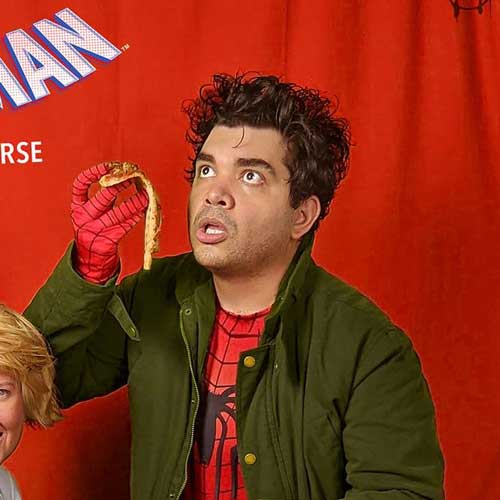 Unepossibly confused man holding a snack in front of a red curtain background, wearing casual clothes.