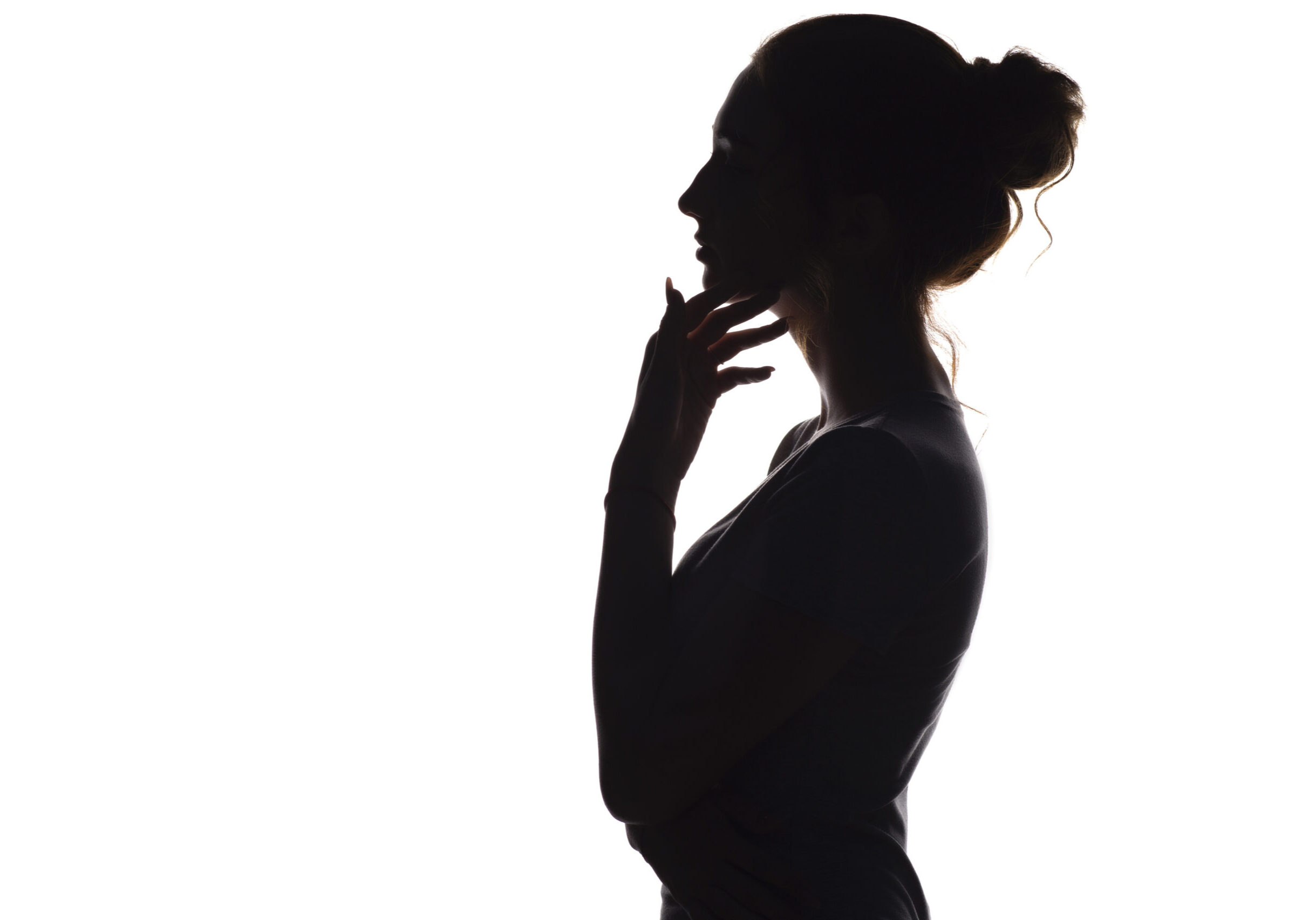 silhouette of a young graceful woman with hand near chin on a white isolated background, face profile of a beautiful girl with handpicked hair, concept beauty and fashion