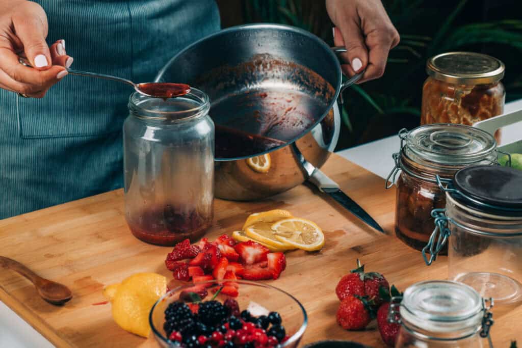 Pouring fruit jam into a jar, canning at home.
