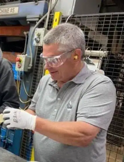 Former WAF president Bob Braun wearing safety glasses and gloves, smiling, onsite at Wisconsin Aluminum Foundry.