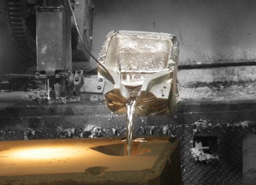 Melted aluminum pouring from a ladel into a mold.
