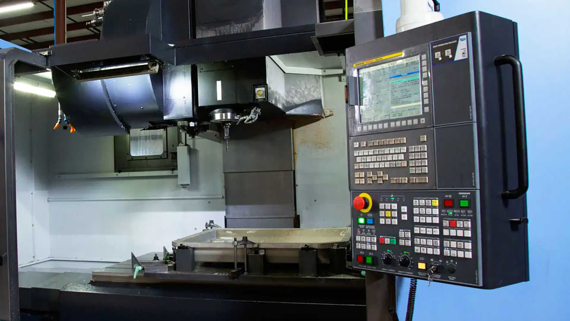 CNC machine and control panel, with a cast aluminum part visible on the machine bed.