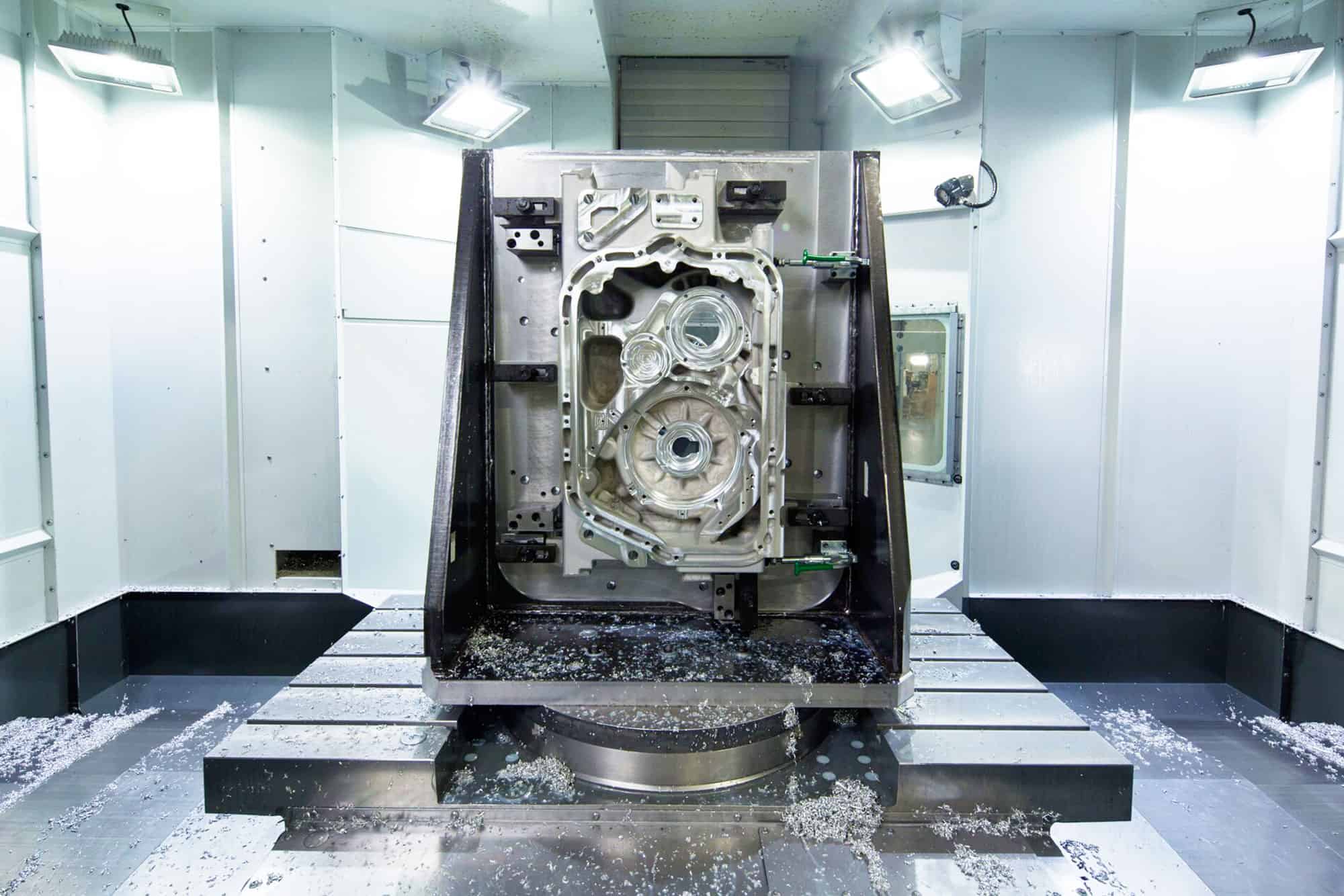 Large cast aluminum part is machined with a horizontal machining center in a room with bright lights.