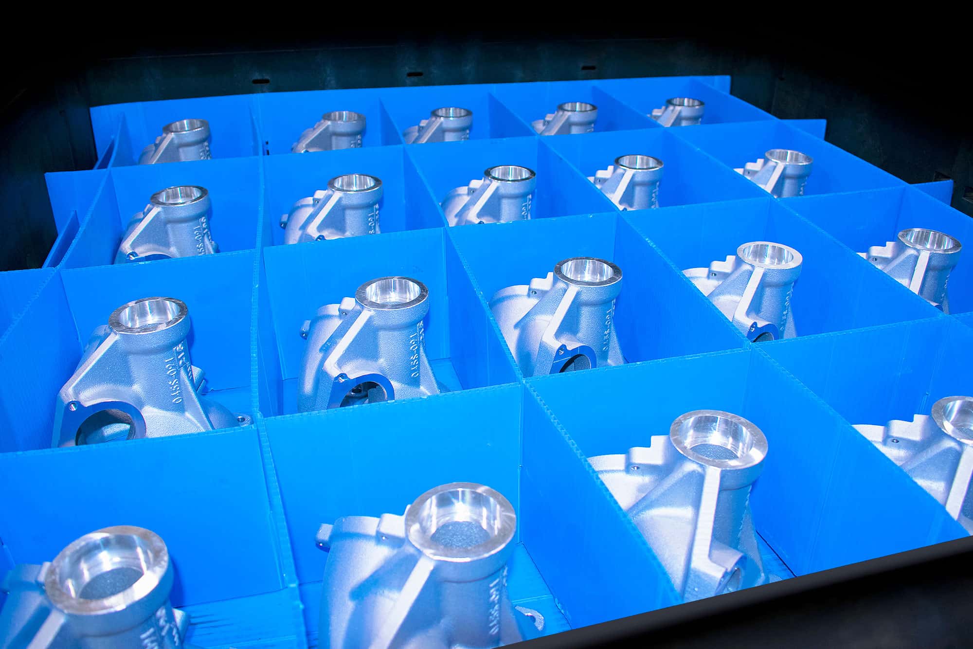Four by four blue crate of machined aluminum parts.