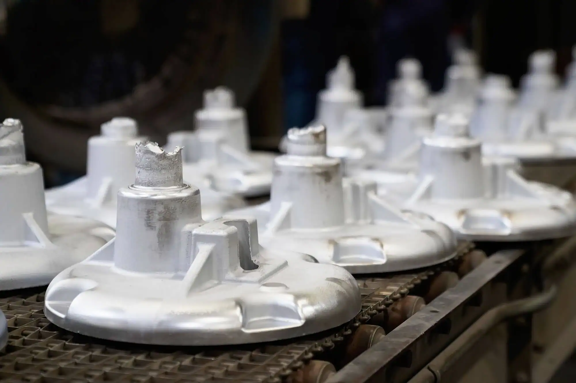 Low pressure permanent mold castings rest on conveyor.
