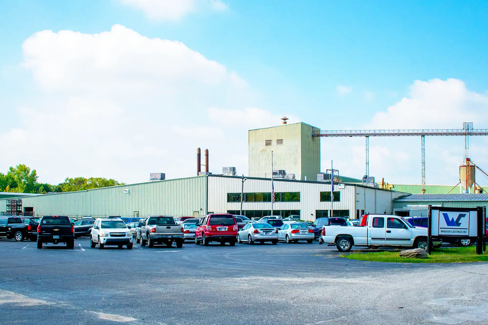 Exterior street view with vehicles parked in a parking lot in front of Wabash Castings' main facility.