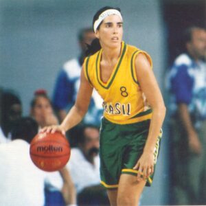 A woman in a green and yellow uniform holding a basketball, showcasing the history of women's basketball. A woman in a green and yellow uniform holding a basketball, showcasing the history of women's basketball.
