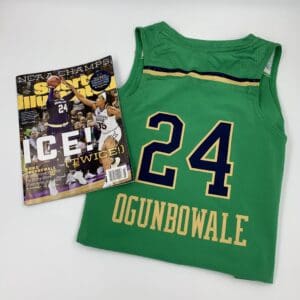 A green jersey showcasing the rich history of women's basketball with a magazine nearby. A green jersey showcasing the rich history of women's basketball with a magazine nearby.