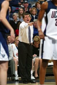 A coach pointing to a player on the court, demonstrating their expertise in women's basketball. A coach pointing to a player on the court, demonstrating their expertise in women's basketball.