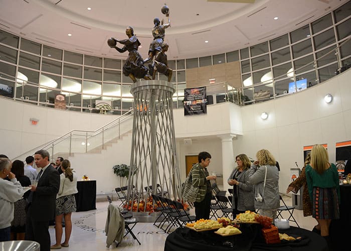 A group of people standing around a table at a Hall of Fame event. A group of people standing around a table at a Hall of Fame event.