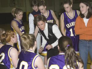 A basketball coach discussing the history of women's basketball with a group of girls. A basketball coach discussing the history of women's basketball with a group of girls.