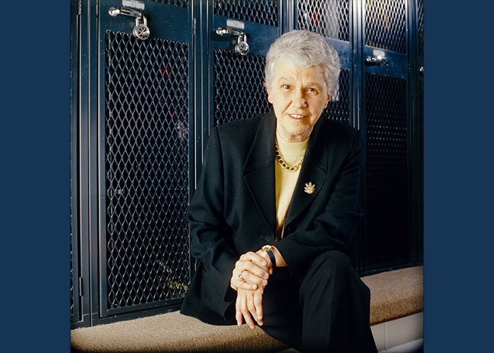 A woman sitting on a bench in front of lockers.