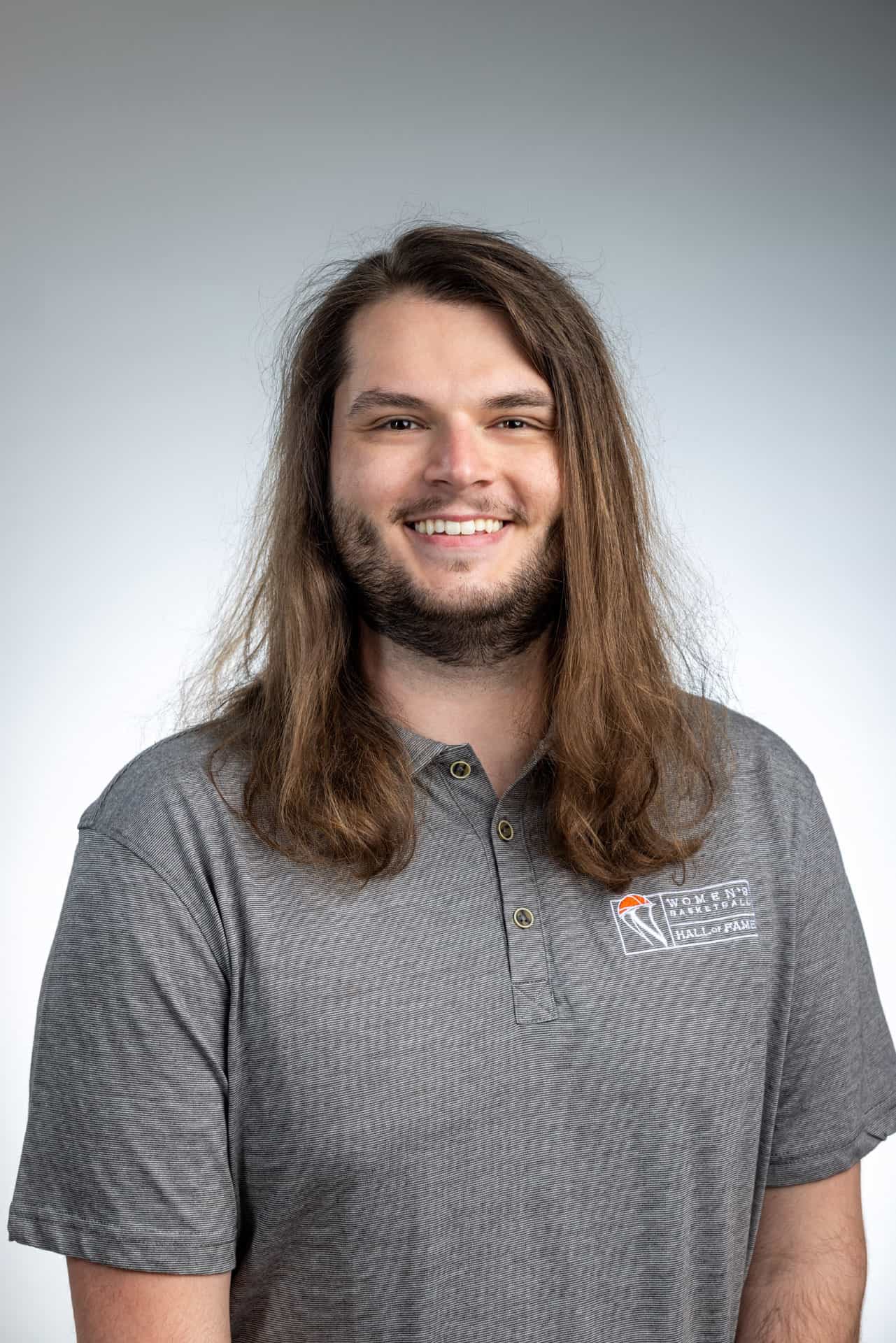 A man with long hair and a gray polo shirt, working as Women's Basketball Hall of Fame staff. A man with long hair and a gray polo shirt, working as Women's Basketball Hall of Fame staff.