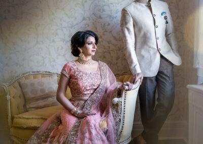 An indian bride and groom posing in front of a window.