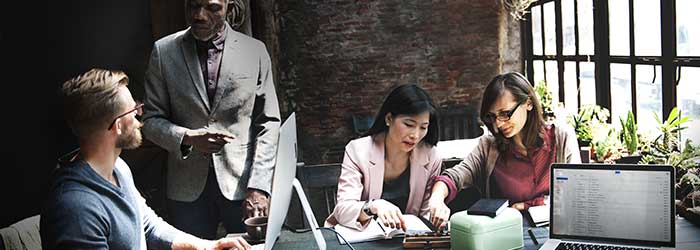 Efficient business meeting with diverse team collaborating on digital devices in a modern office.