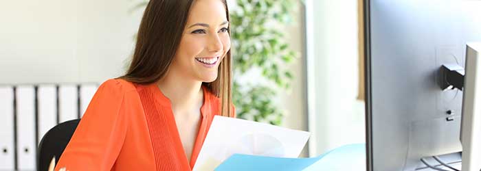 Professional woman working on business documents at office desk for West X Business Solutions.