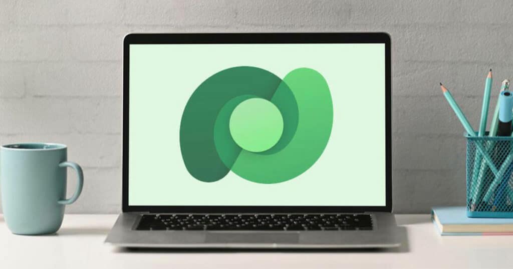 Laptop displaying abstract green logo for West X Business Solutions on desk.