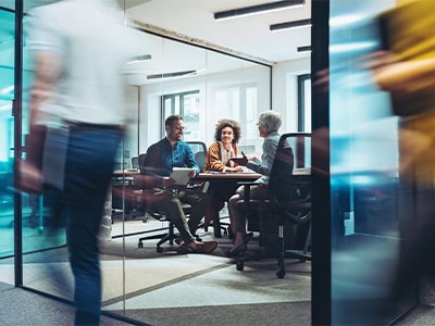 Young Professionals meeting in a boardroom surrounded by a fast-paced work environment