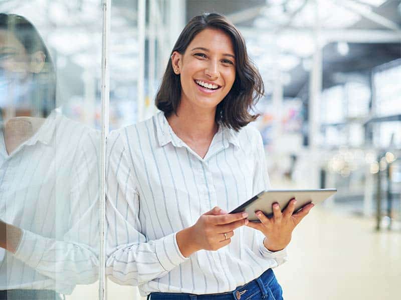 Smiling woman with tablet in modern office setting for business solutions SEO.