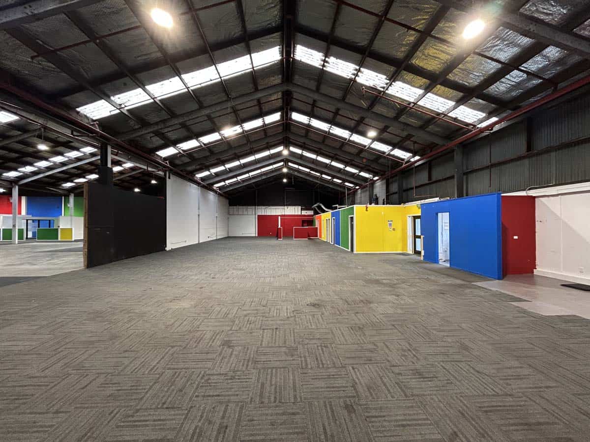 Interior view of a spacious warehouse with colorful storage units and high ceilings.