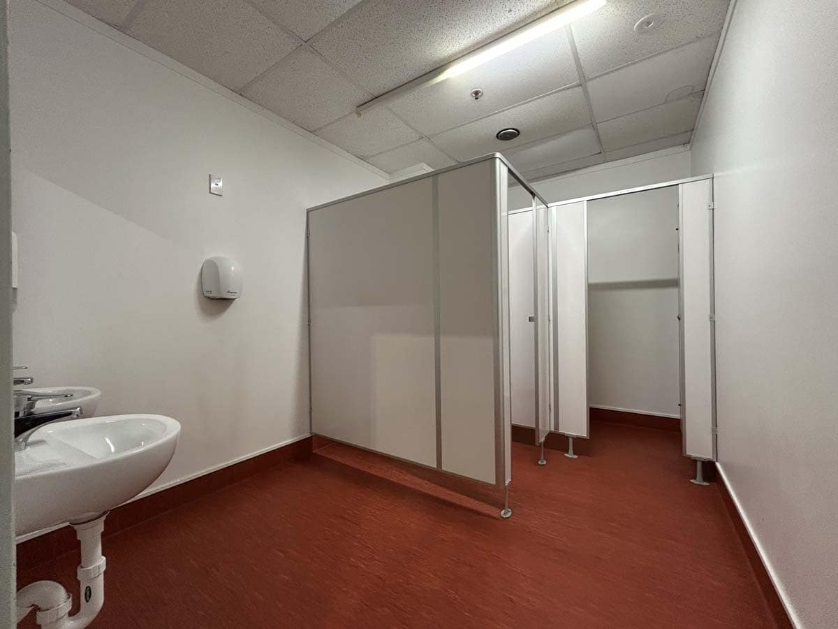 Clean, accessible public bathroom with privacy cubicles and handbasin.