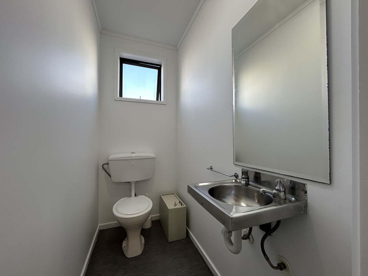 Small bathroom with toilet, sink, and window at 107 Corbett Road.
