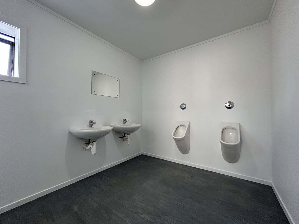 Interior view of a clean, modern restroom with two urinals and two sinks.