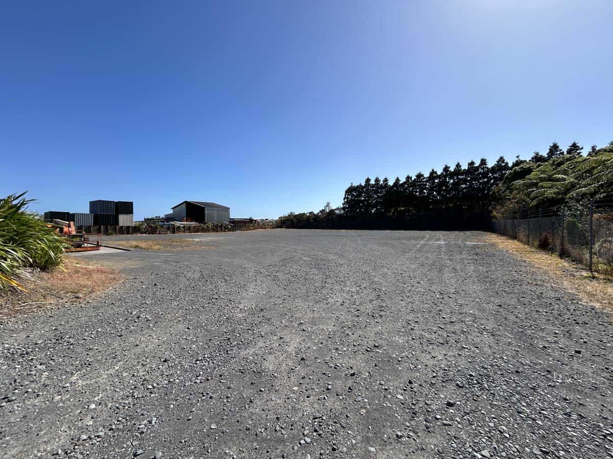 Open gravel lot at 107 Corbett Road with clear blue sky and surrounding trees.