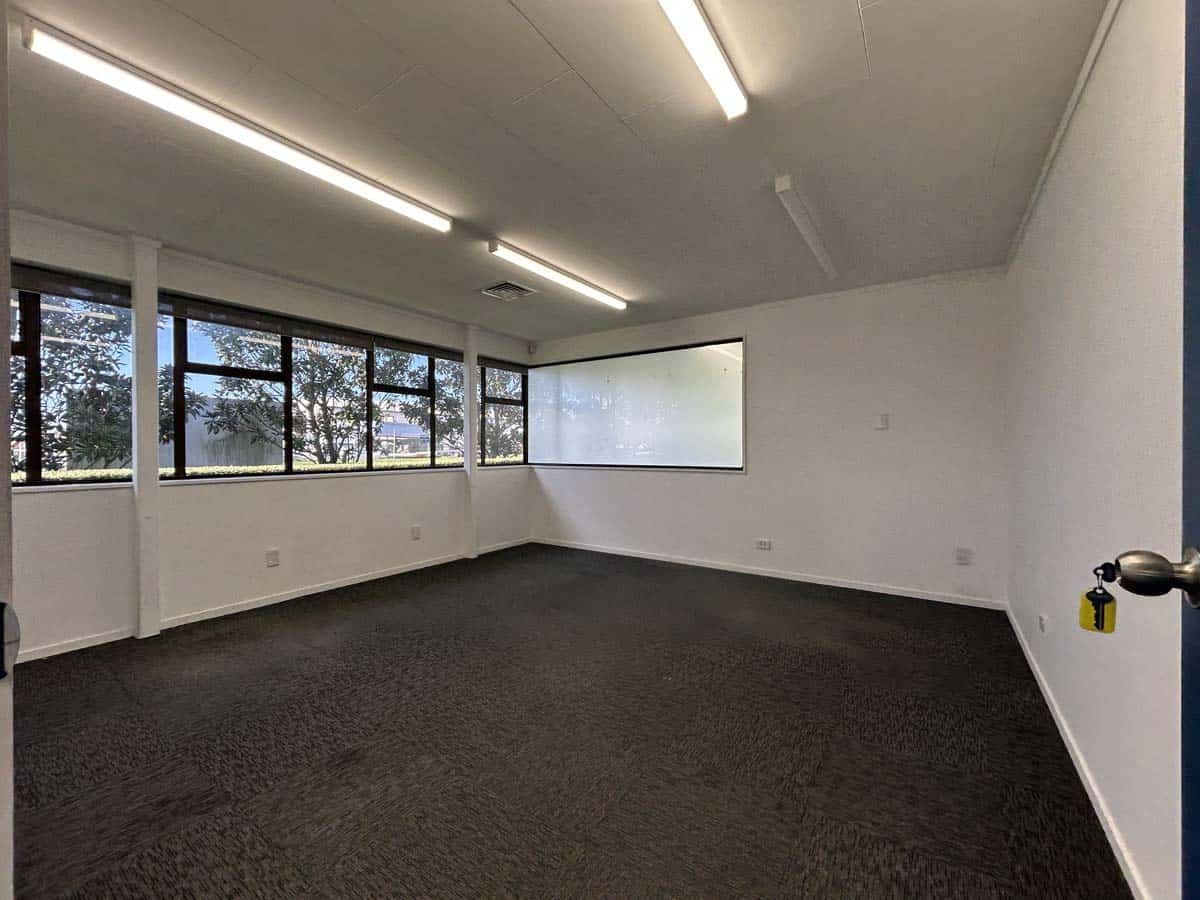 Bright, empty office room with large windows and ceiling lights in Auckland.