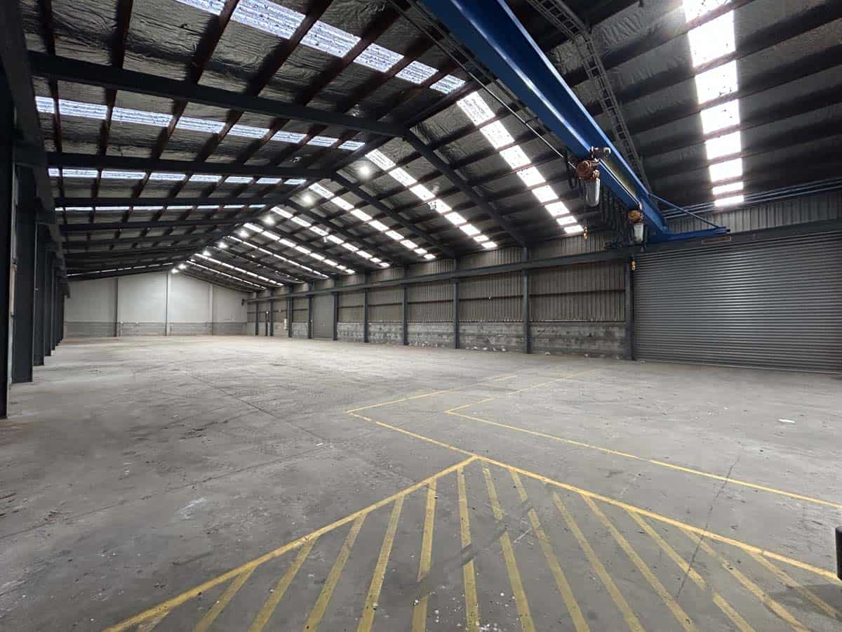 Empty industrial warehouse with high ceilings and overhead crane.