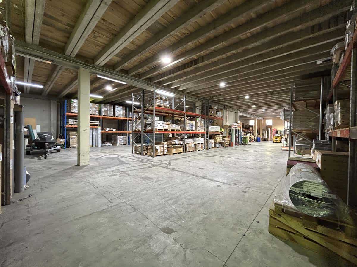 Spacious warehouse interior with storage shelves and industrial equipment.