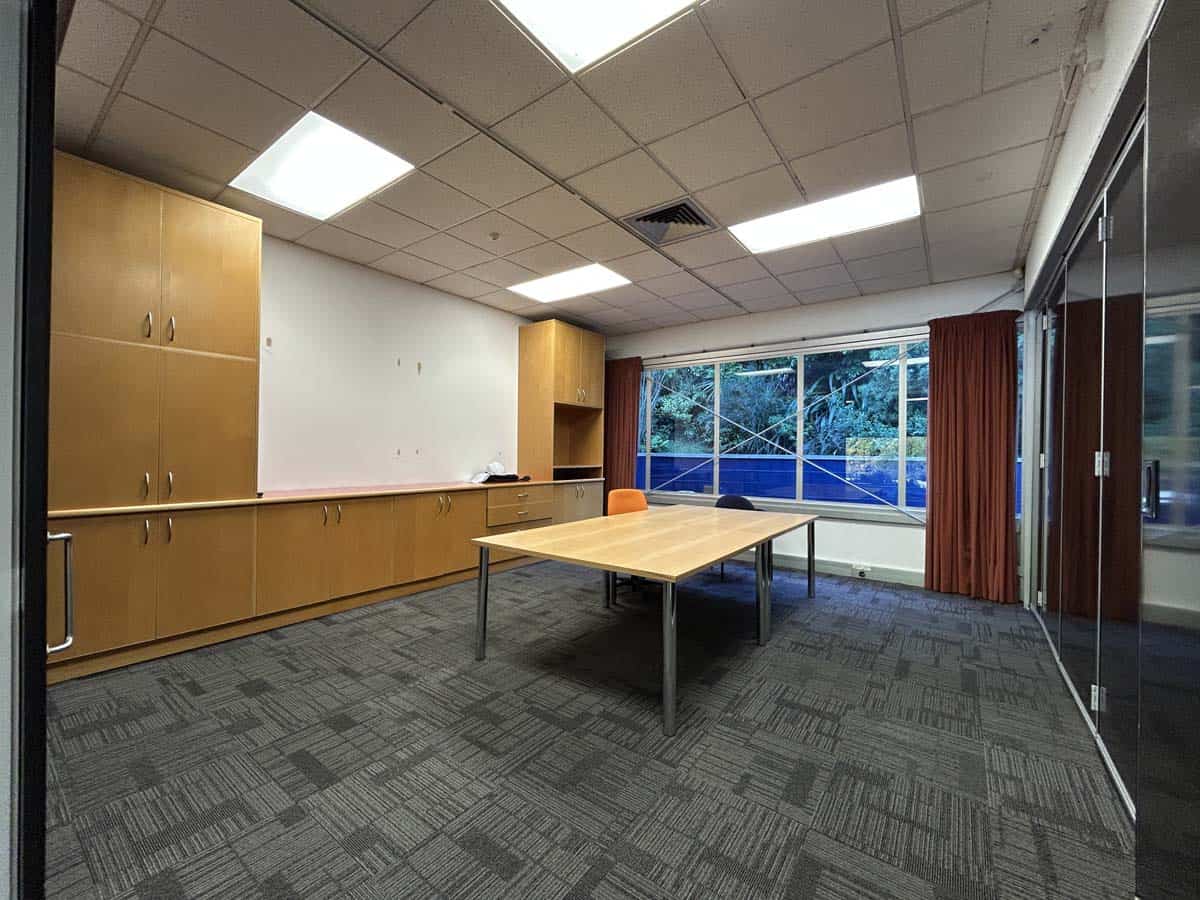 Modern office meeting room with large window, wooden cabinets, and table.