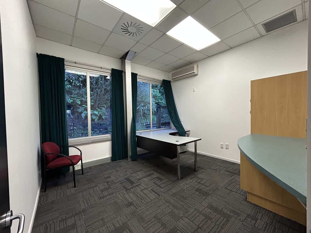 Modern office space with desk, chair, and large windows.