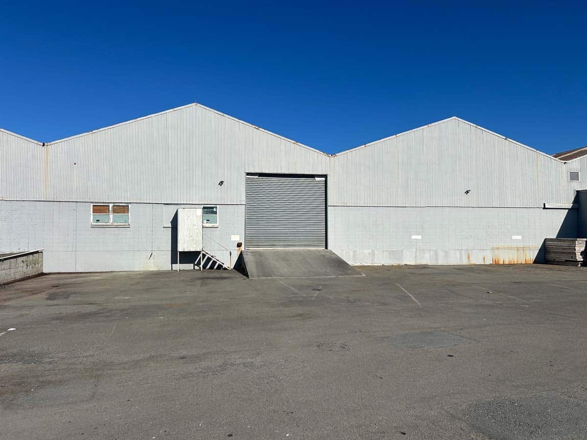 Industrial warehouse with large roller door and clear sky.