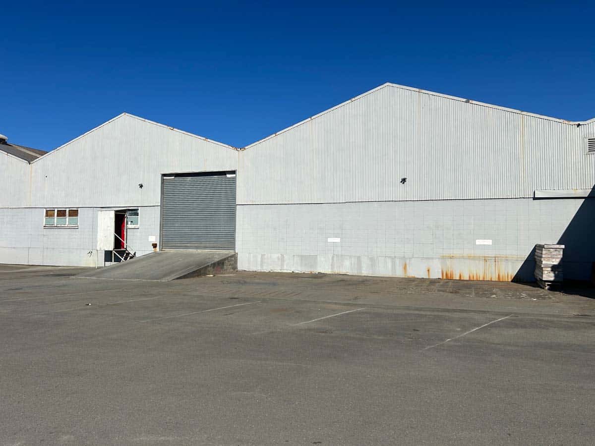 Modern industrial warehouse with large garage door and clear sky.