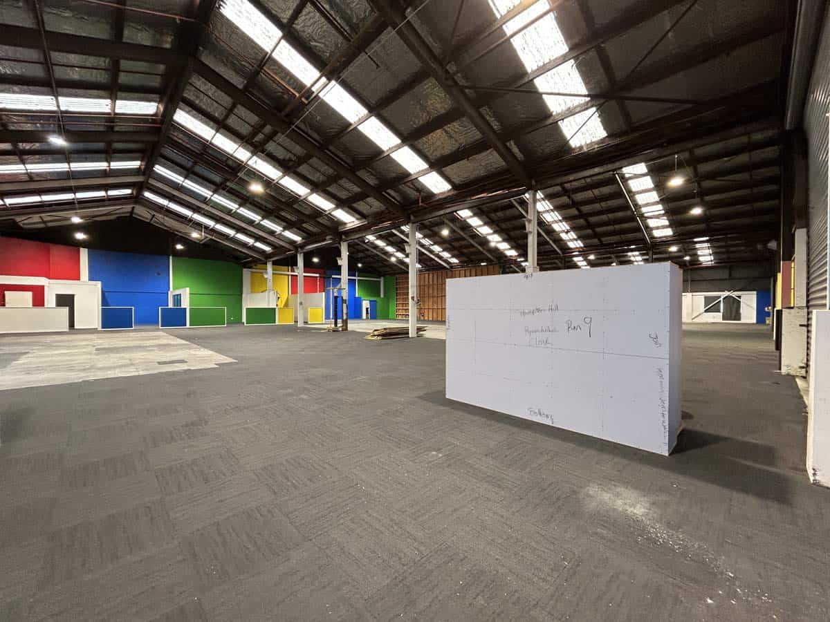 Spacious warehouse with vibrant wall colors, high roof, and open floor area for storage.