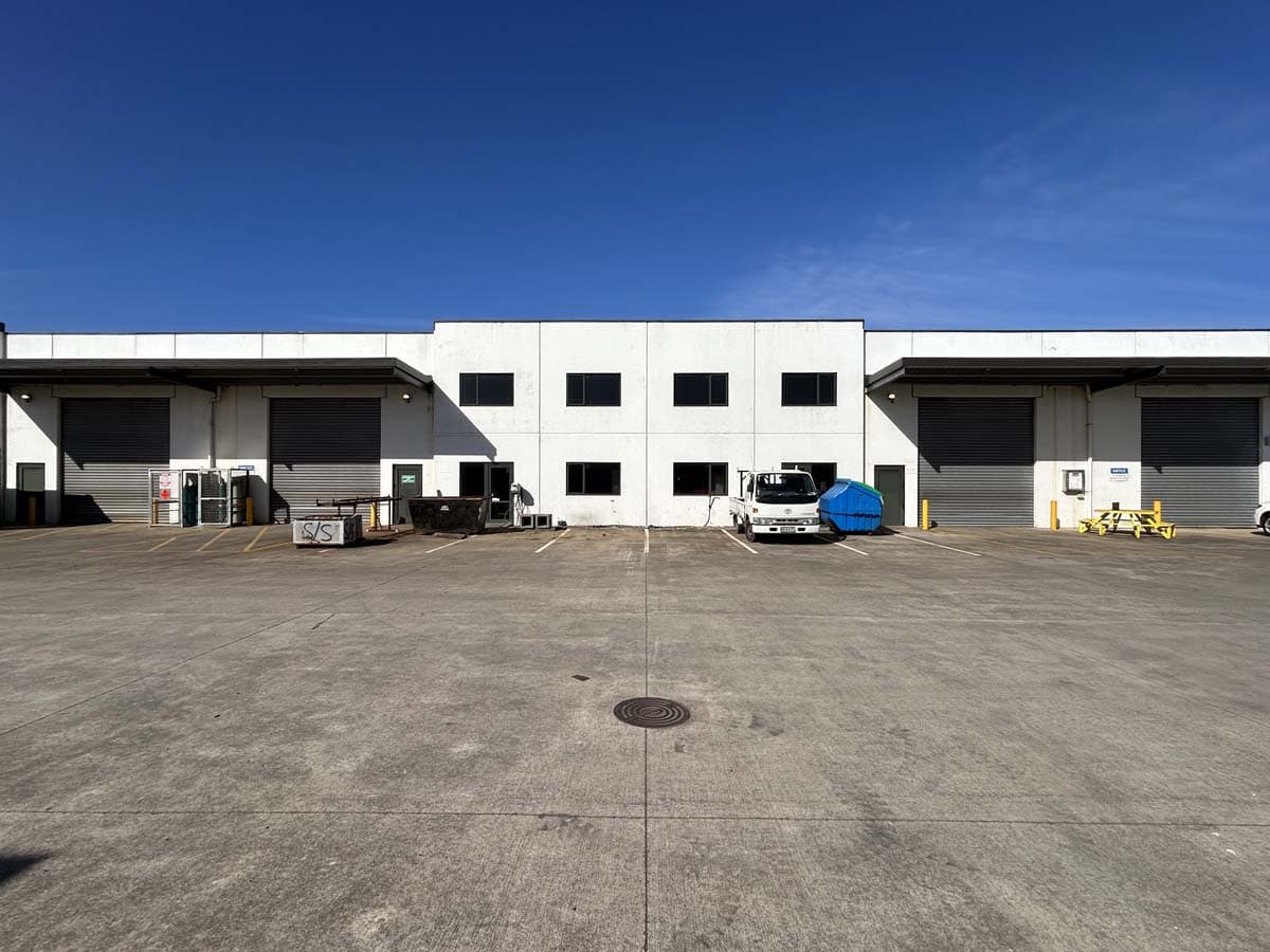 Modern industrial warehouse building with loading docks and parking.