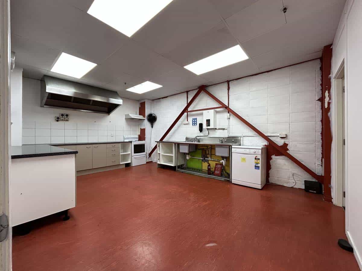 Bright commercial kitchen with white tiled walls and red flooring.
