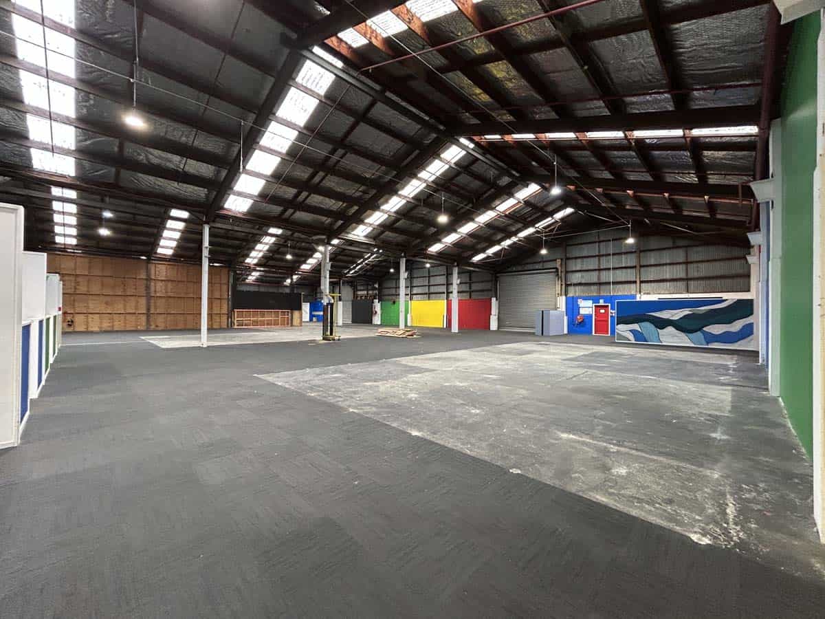 Spacious warehouse with high ceilings, industrial lighting, and colorful wall accents.