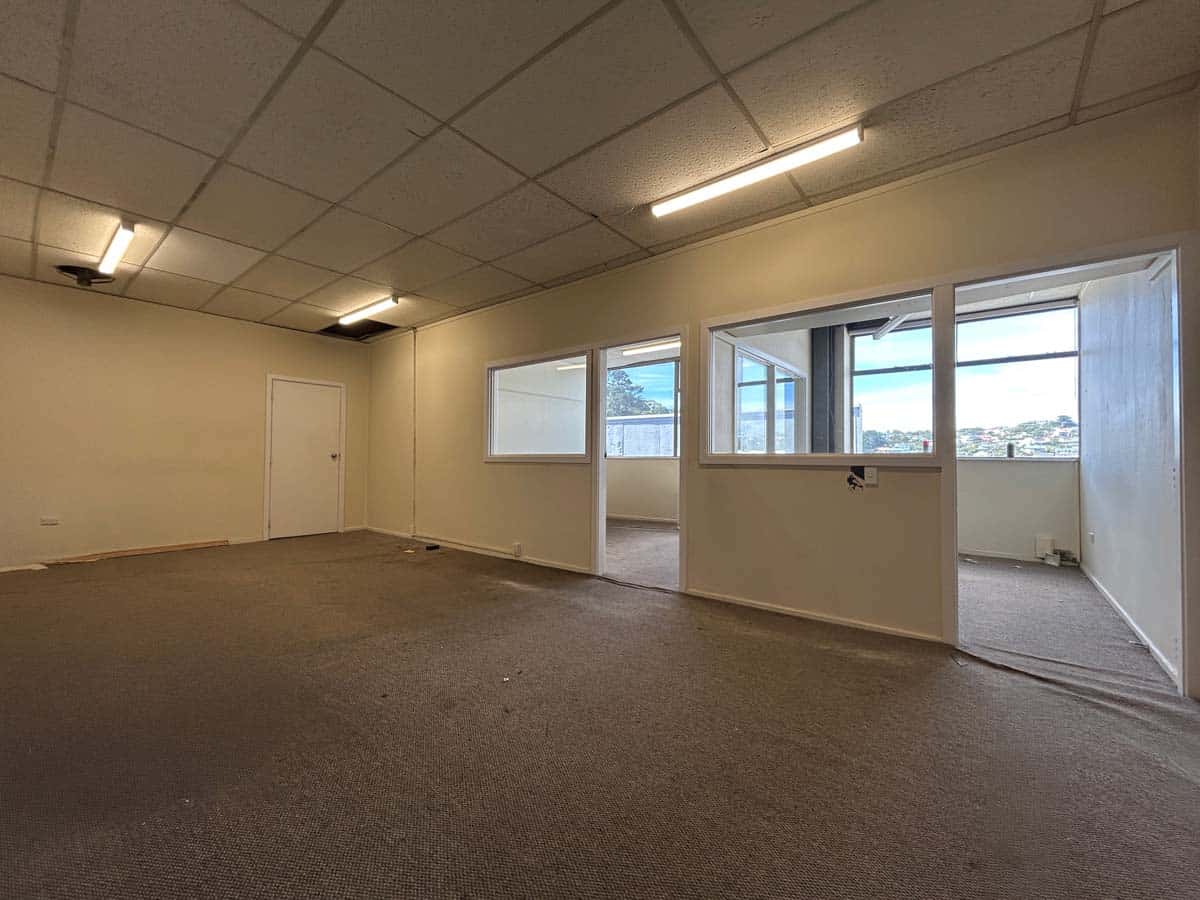 Spacious commercial office interior with large windows and neutral decor.