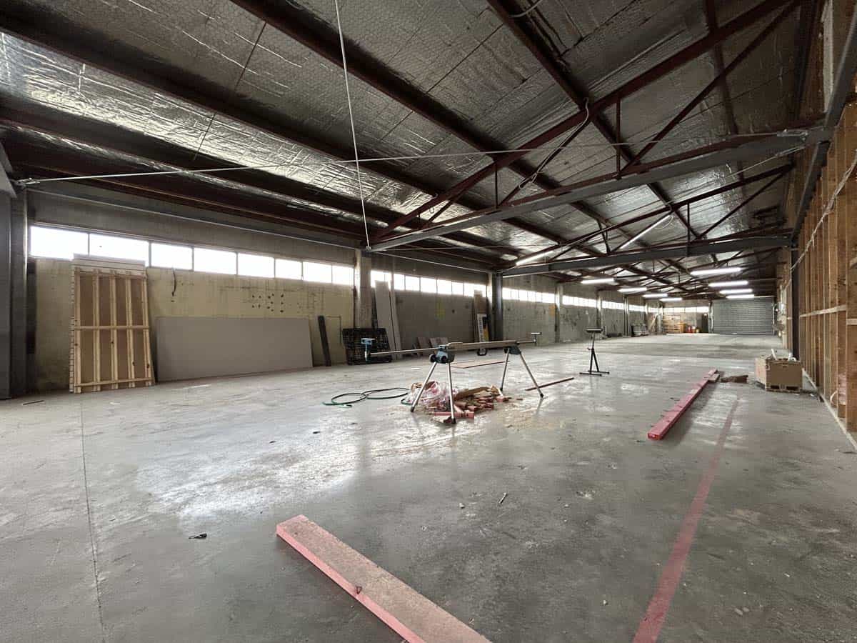 Construction site interior with unfinished flooring and structural elements.