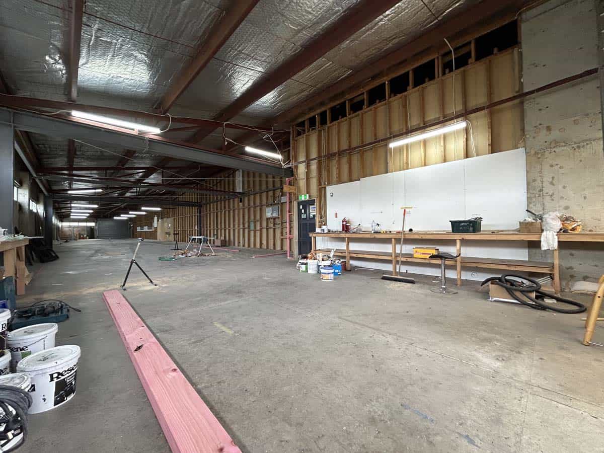 Interior view of a spacious industrial workshop with construction materials and tools.