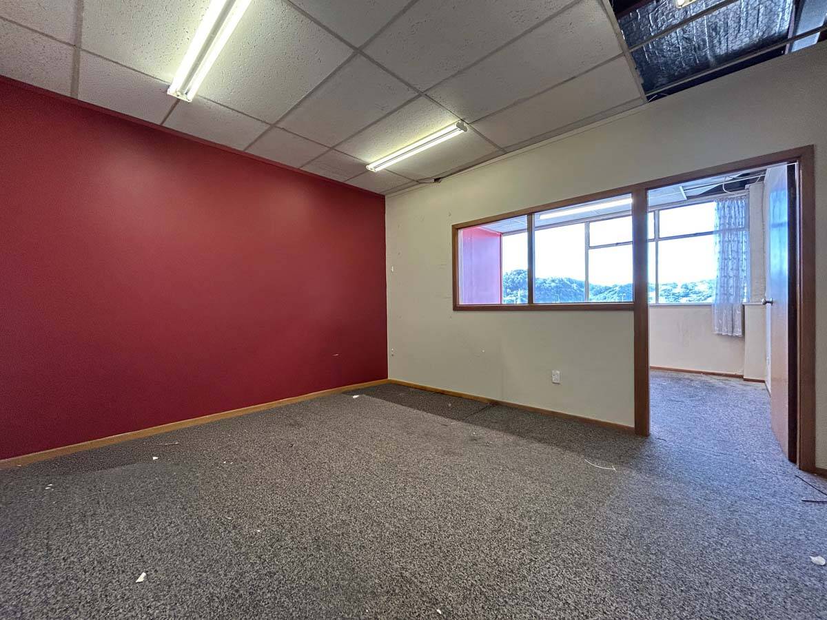 Bright office room with large window and red accent wall.