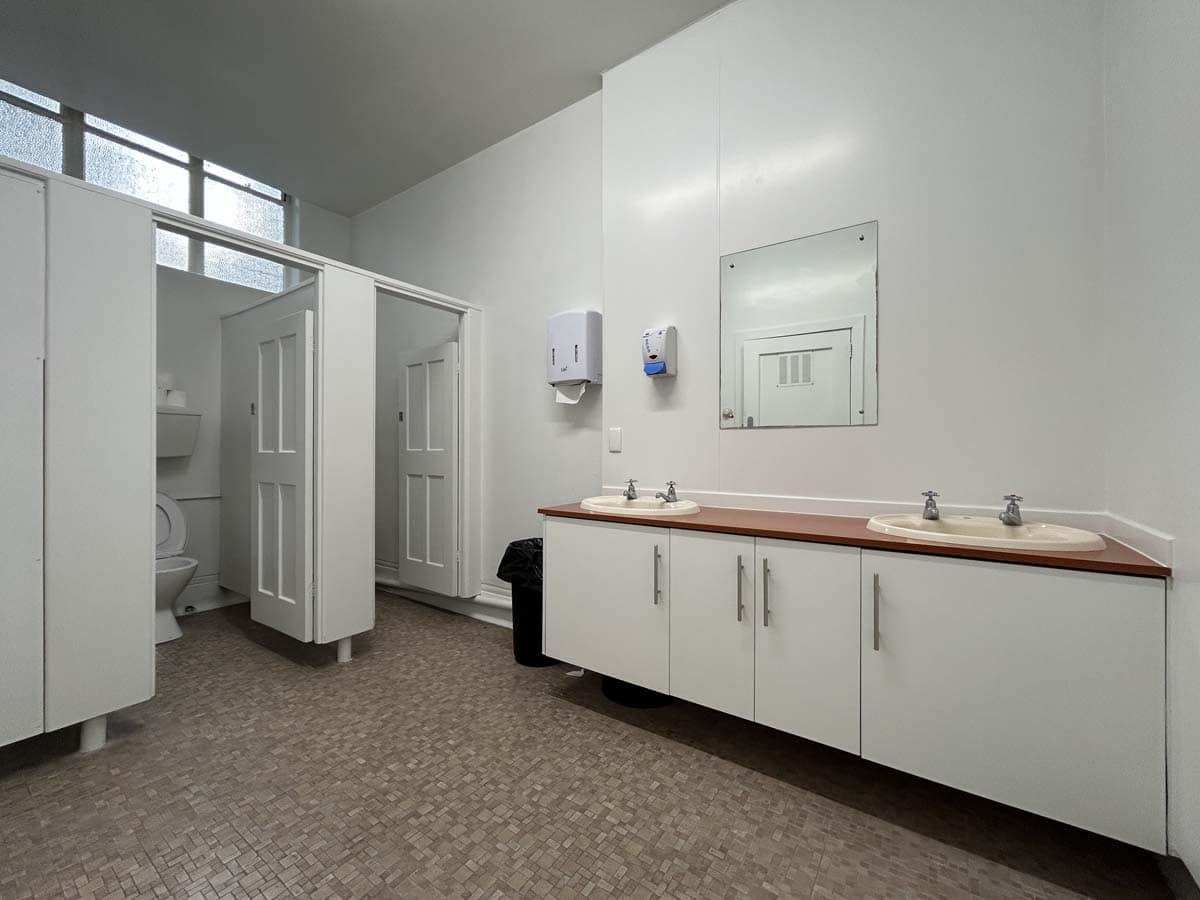 Public restroom with dual sinks and toilet stalls at 38 Devon Street West.