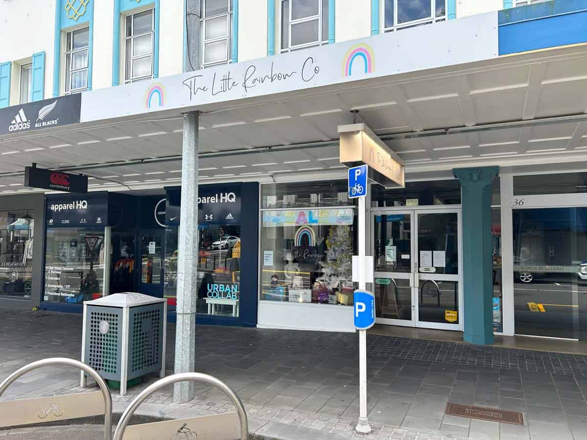 White Lion shopfront on Devon Street West with rainbow sign and parking area.